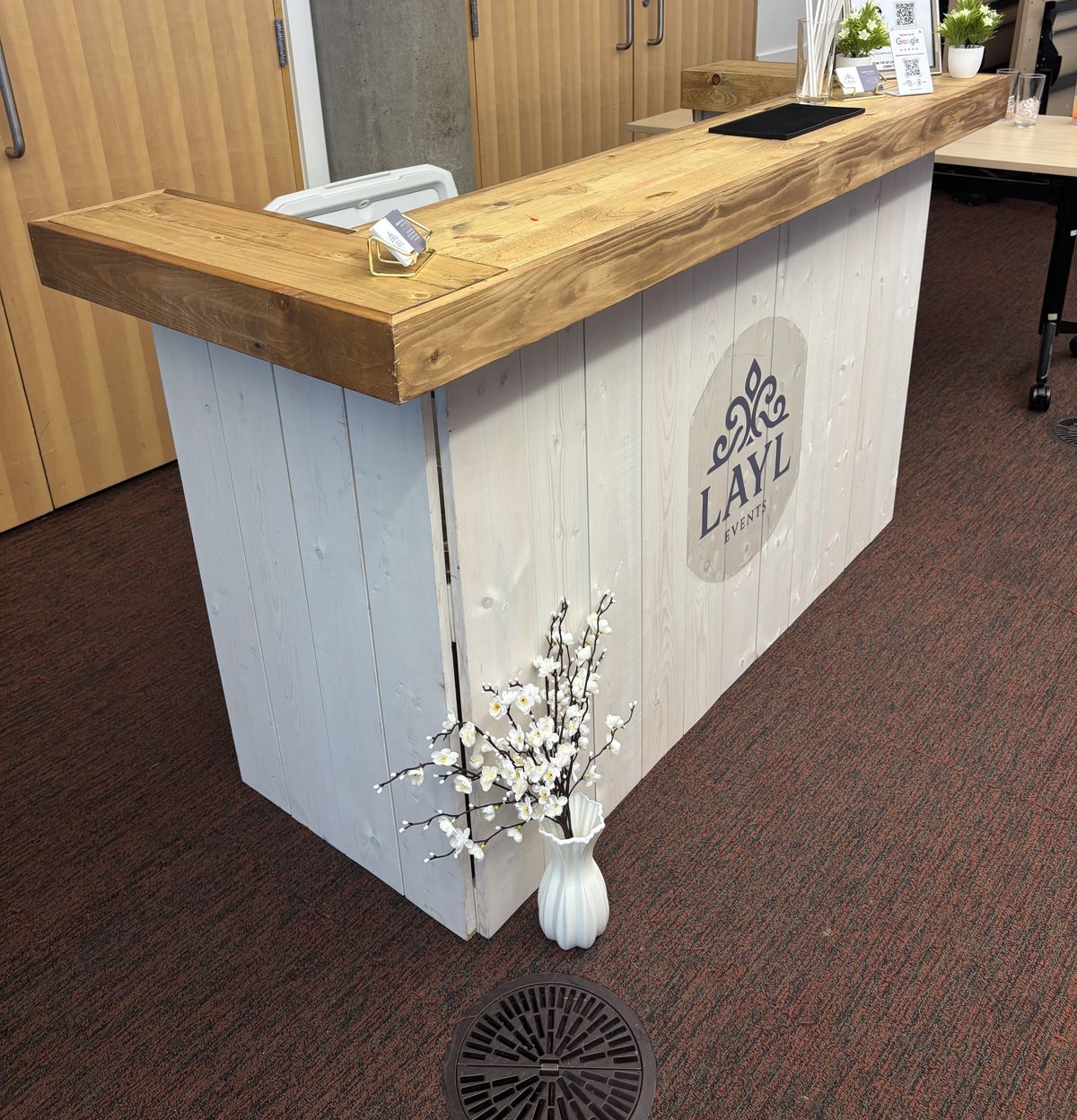 The Layl mocktail bar with its wooden bar top and white panel front, set up indoors