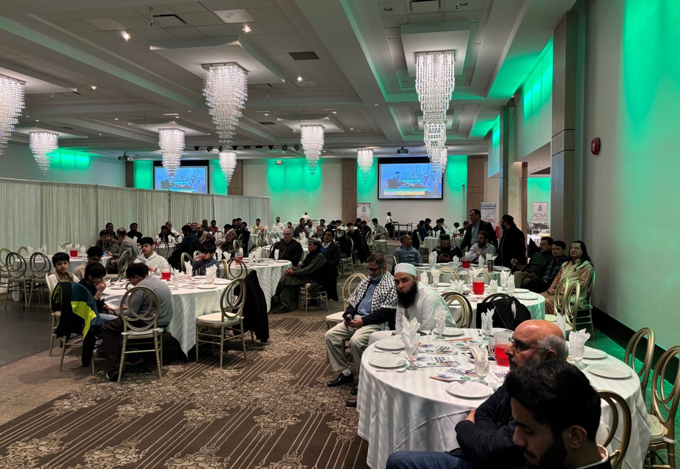 A banquet hall set for an ICNA fundraising dinner, with guests seated at round tables
