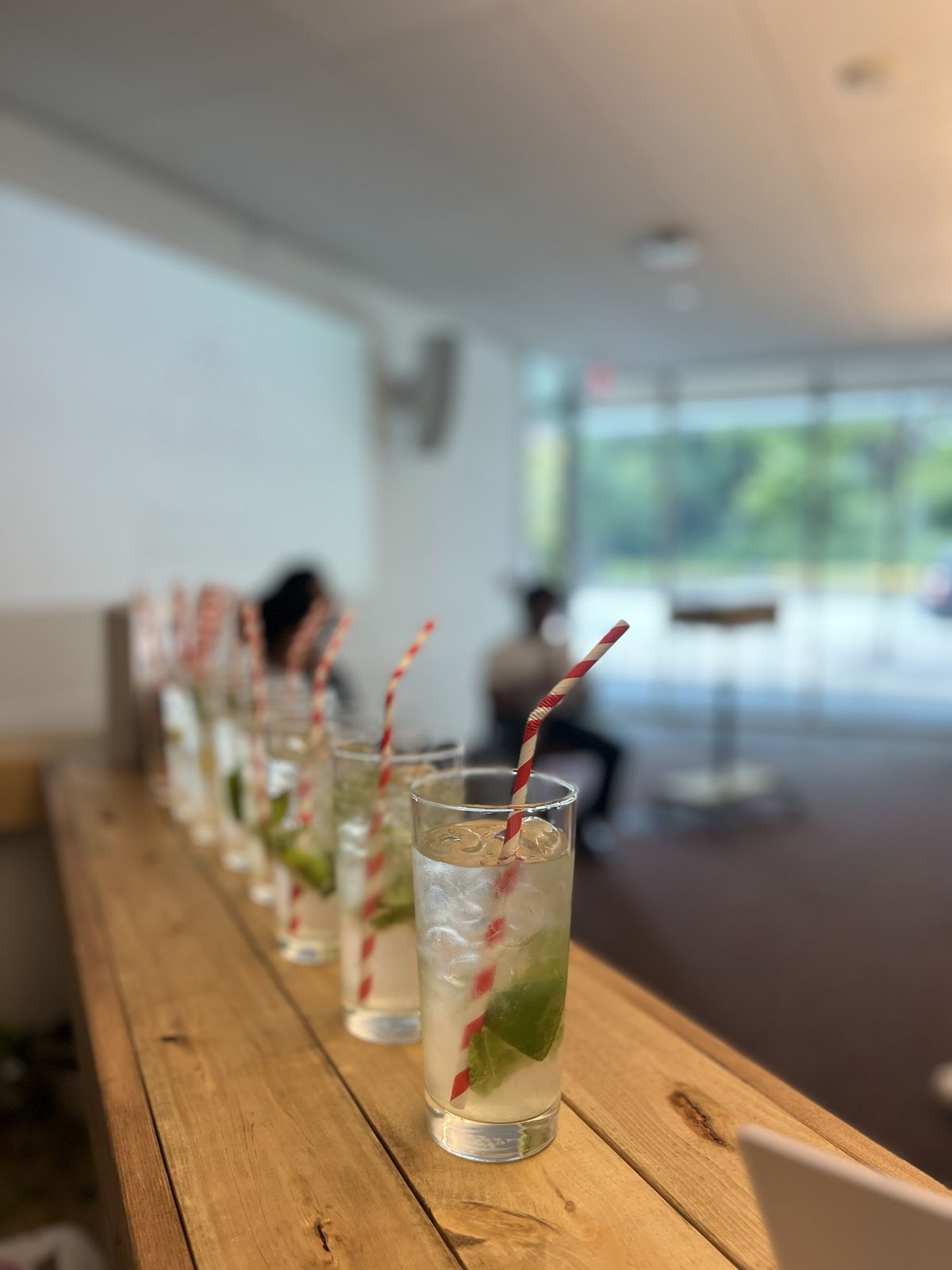 A long row of mint mocktails with striped straws lined up on the bar